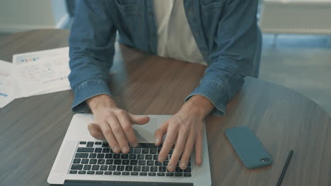 男性手在笔记本电脑远程办公上打字